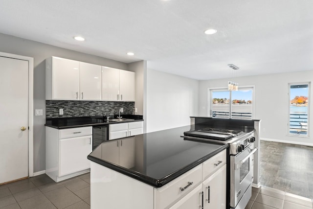 kitchen with white cabinetry, sink, backsplash, pendant lighting, and high end range