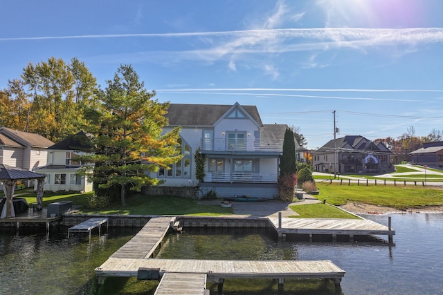 view of dock with a balcony, a lawn, and a water view