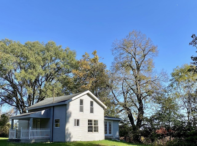 view of side of property with covered porch and a yard