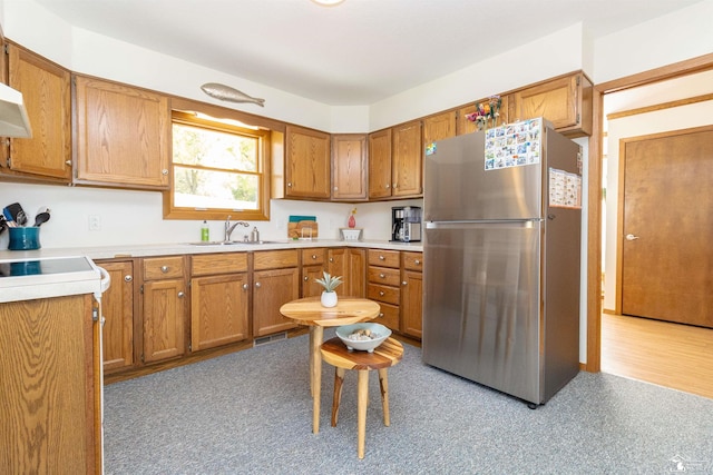 kitchen featuring stainless steel fridge, sink, and light wood-type flooring