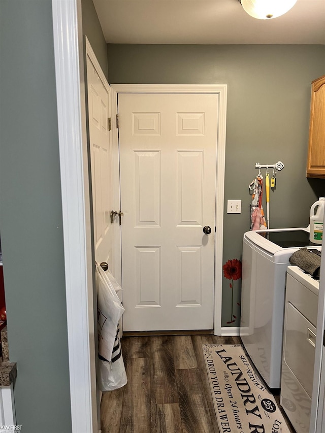 clothes washing area with dark wood-type flooring, washer and clothes dryer, and cabinets