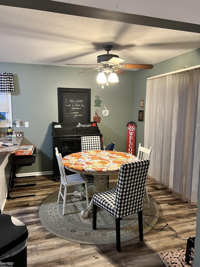 dining room featuring hardwood / wood-style flooring, ceiling fan, and a textured ceiling