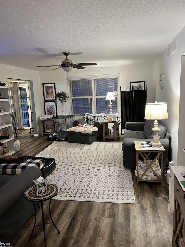 living room with ceiling fan, a textured ceiling, and dark hardwood / wood-style flooring