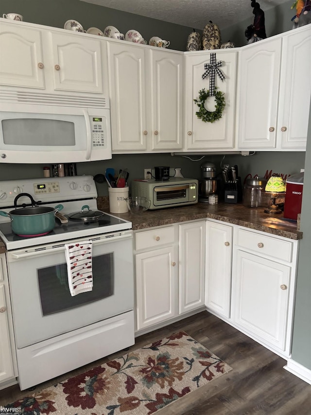 kitchen featuring white cabinetry, dark wood-type flooring, a textured ceiling, and white appliances