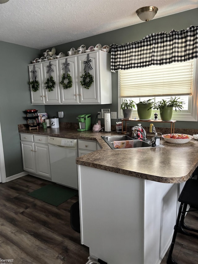 kitchen with sink, dishwasher, white cabinets, dark hardwood / wood-style flooring, and kitchen peninsula