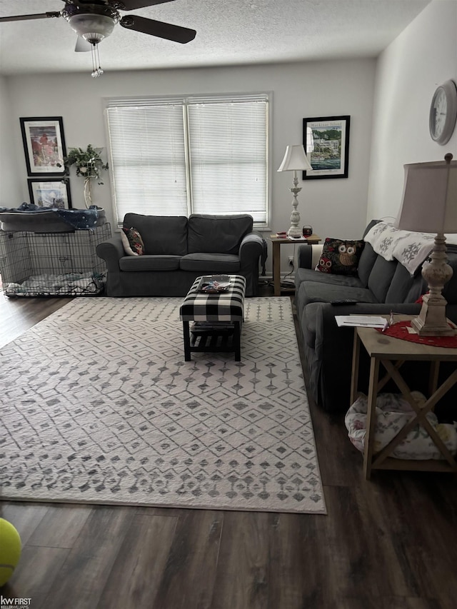 living room featuring ceiling fan, dark hardwood / wood-style flooring, and a textured ceiling