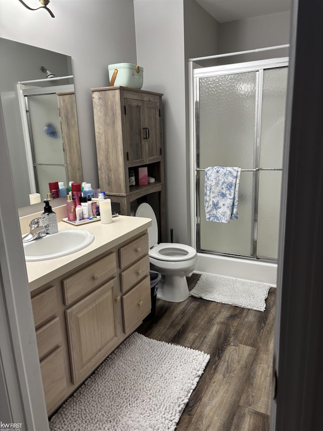 bathroom with vanity, wood-type flooring, a shower with door, and toilet