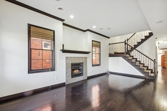 unfurnished living room with a tile fireplace, hardwood / wood-style flooring, plenty of natural light, and ornamental molding