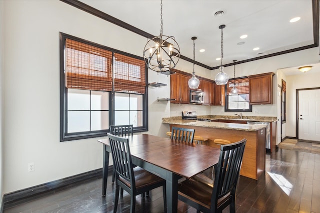 dining area with sink, dark wood-type flooring, a notable chandelier, and ornamental molding