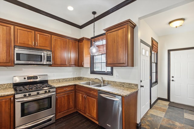 kitchen featuring pendant lighting, sink, ornamental molding, appliances with stainless steel finishes, and light stone counters