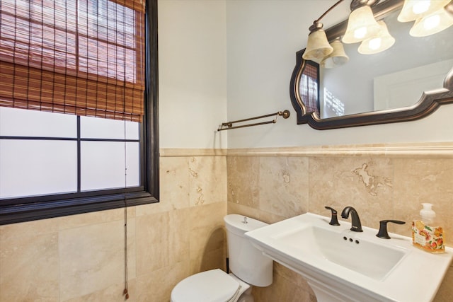 bathroom with toilet, sink, and tile walls