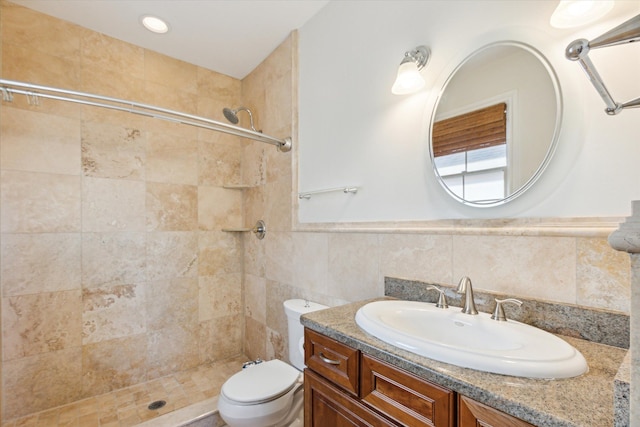 bathroom featuring tiled shower, toilet, tile walls, and vanity