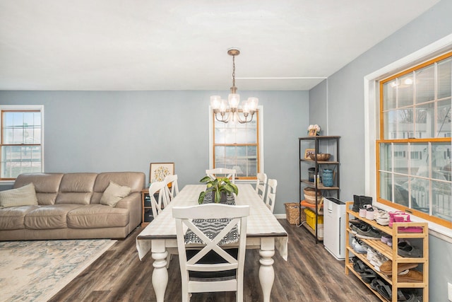 dining area featuring dark wood-type flooring and an inviting chandelier