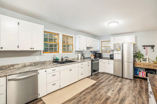 kitchen with white cabinetry, sink, dark hardwood / wood-style flooring, dark stone countertops, and appliances with stainless steel finishes