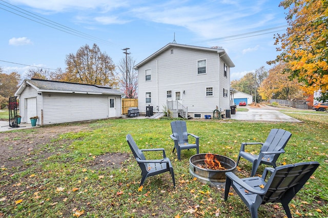 rear view of house with an outbuilding, a garage, an outdoor fire pit, and a lawn