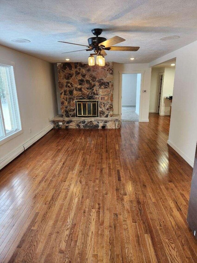 unfurnished living room with hardwood / wood-style flooring, ceiling fan, a fireplace, and a textured ceiling