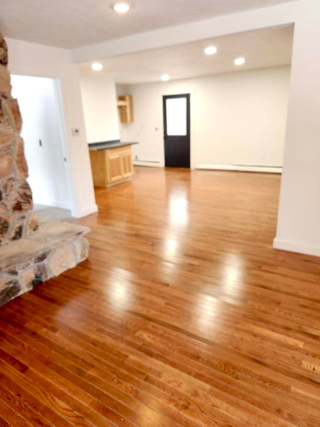 unfurnished living room featuring a stone fireplace and hardwood / wood-style floors