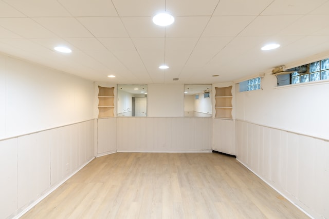 basement featuring built in shelves and light hardwood / wood-style floors