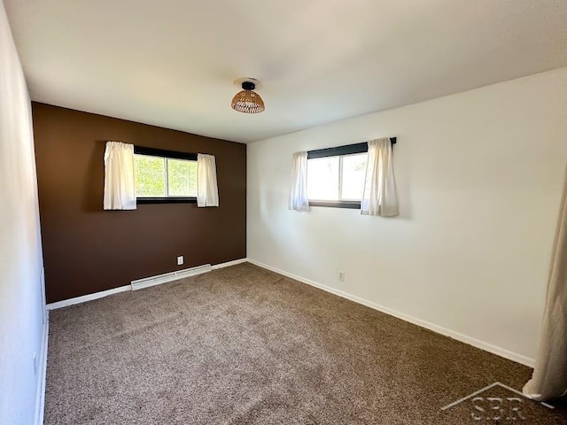 empty room featuring dark colored carpet and a baseboard heating unit