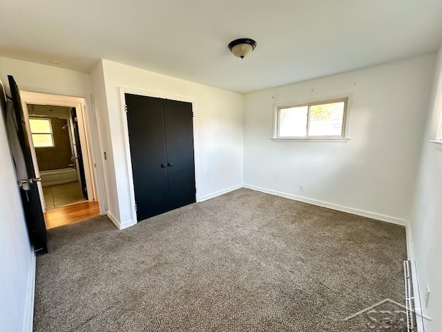 unfurnished bedroom with multiple windows, a closet, and dark colored carpet