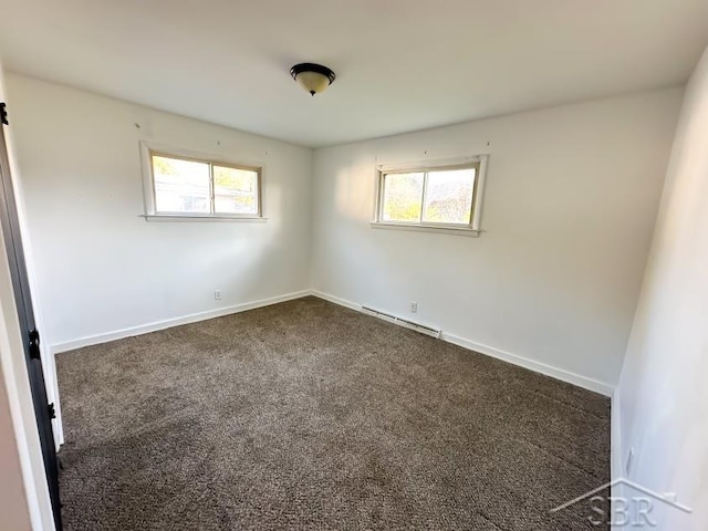 spare room featuring dark colored carpet and a baseboard heating unit