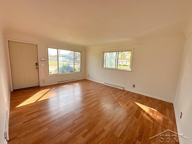 spare room with a wealth of natural light, a baseboard radiator, and hardwood / wood-style flooring