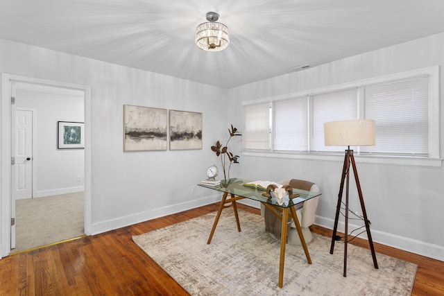 home office featuring wood-type flooring and an inviting chandelier