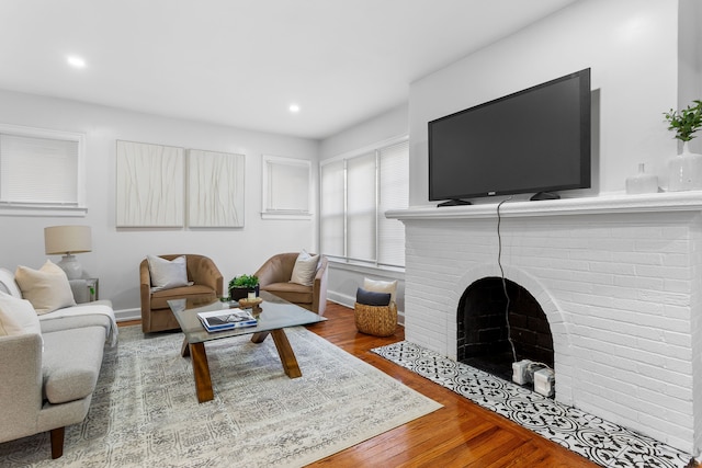 living room featuring hardwood / wood-style flooring and a brick fireplace