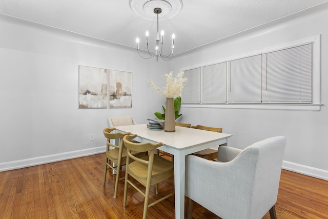 dining area with wood-type flooring and a chandelier