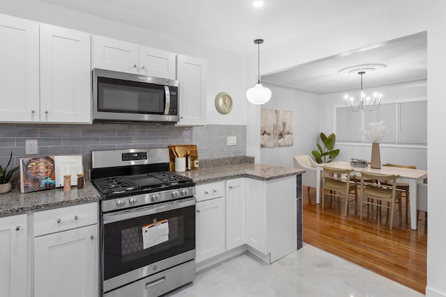 kitchen featuring decorative backsplash, white cabinets, decorative light fixtures, and appliances with stainless steel finishes