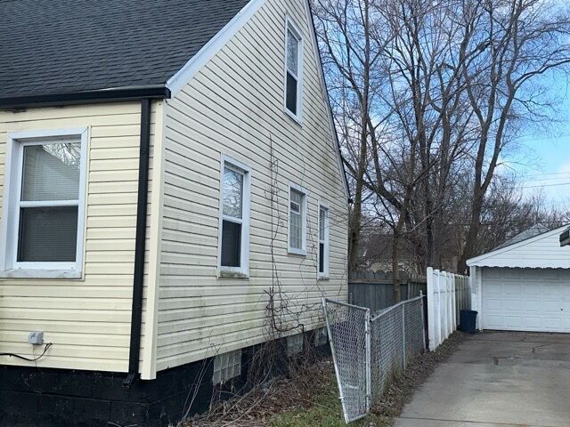 20543 Waltham St, Detroit, MI 48205 - view of side of property featuring a shingled roof, a detached garage, and an outdoor structure