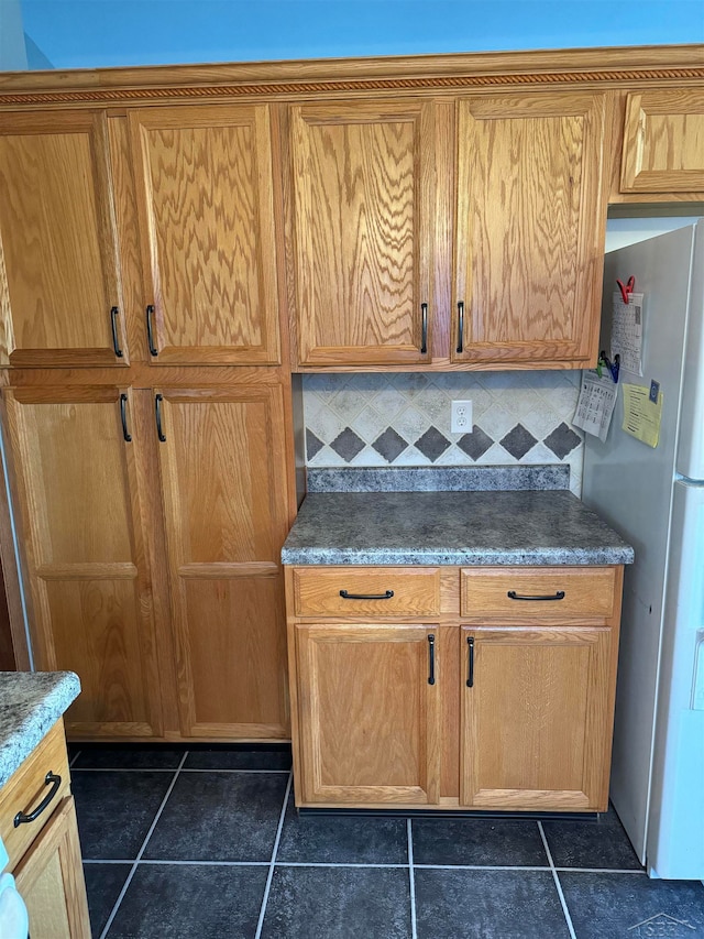 kitchen with dark tile patterned flooring, stainless steel fridge, and tasteful backsplash