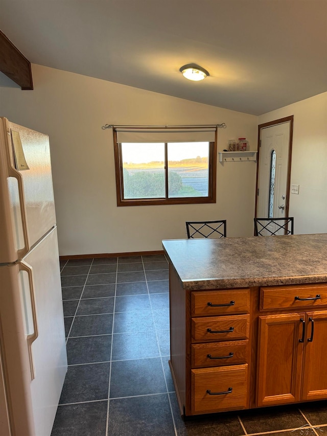 kitchen with dark tile patterned flooring, white refrigerator, and lofted ceiling