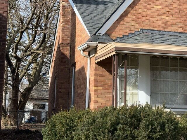 17401 W Albion St W, Detroit, MI 48234 - view of side of home featuring a shingled roof, brick siding, and a chimney