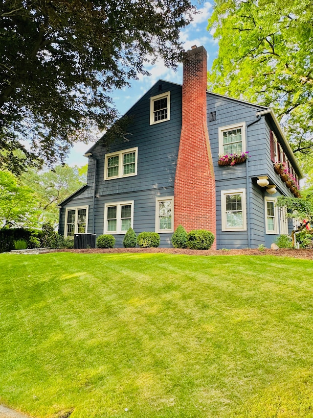 rear view of property featuring a yard and central air condition unit