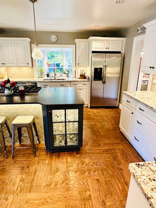 kitchen with sink, white cabinets, hanging light fixtures, and stainless steel refrigerator with ice dispenser