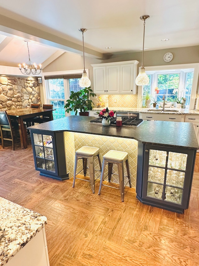 kitchen featuring pendant lighting, white cabinetry, a breakfast bar area, and sink