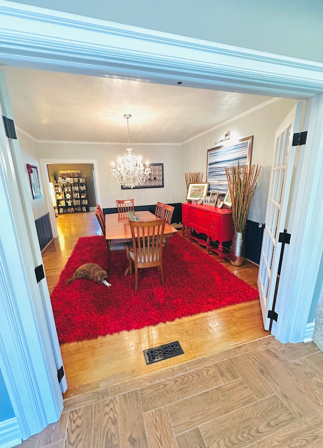 dining space featuring wood-type flooring, an inviting chandelier, and ornamental molding