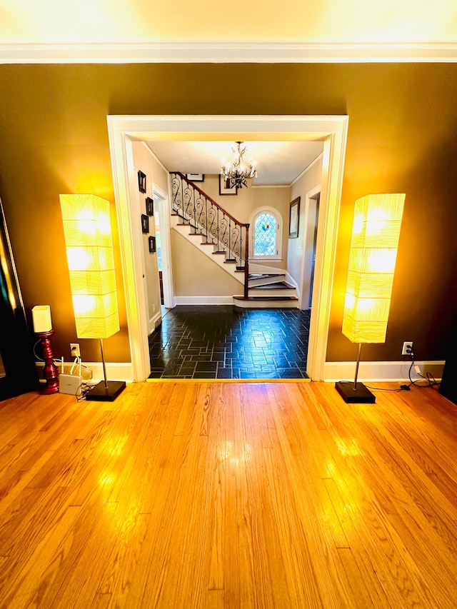 entrance foyer with hardwood / wood-style flooring, an inviting chandelier, and crown molding