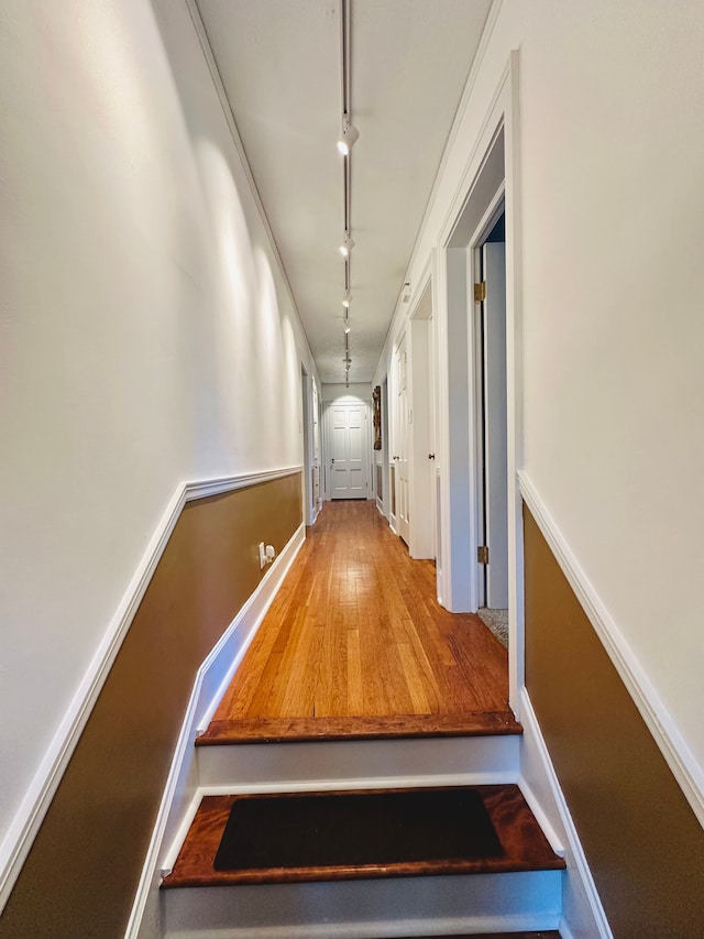 hall with wood-type flooring and track lighting