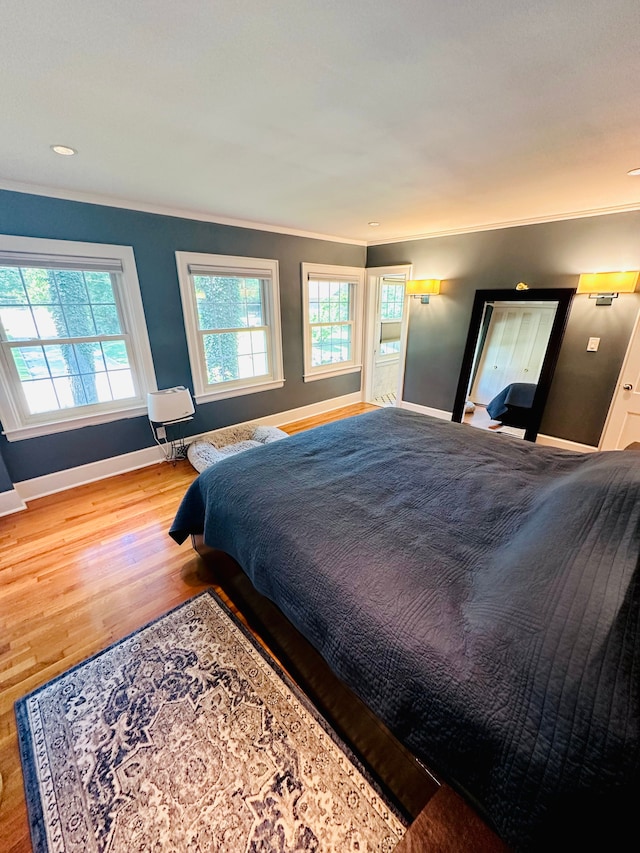 bedroom featuring multiple windows, hardwood / wood-style floors, and ornamental molding