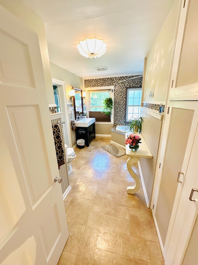 bathroom featuring a washtub, toilet, and vanity