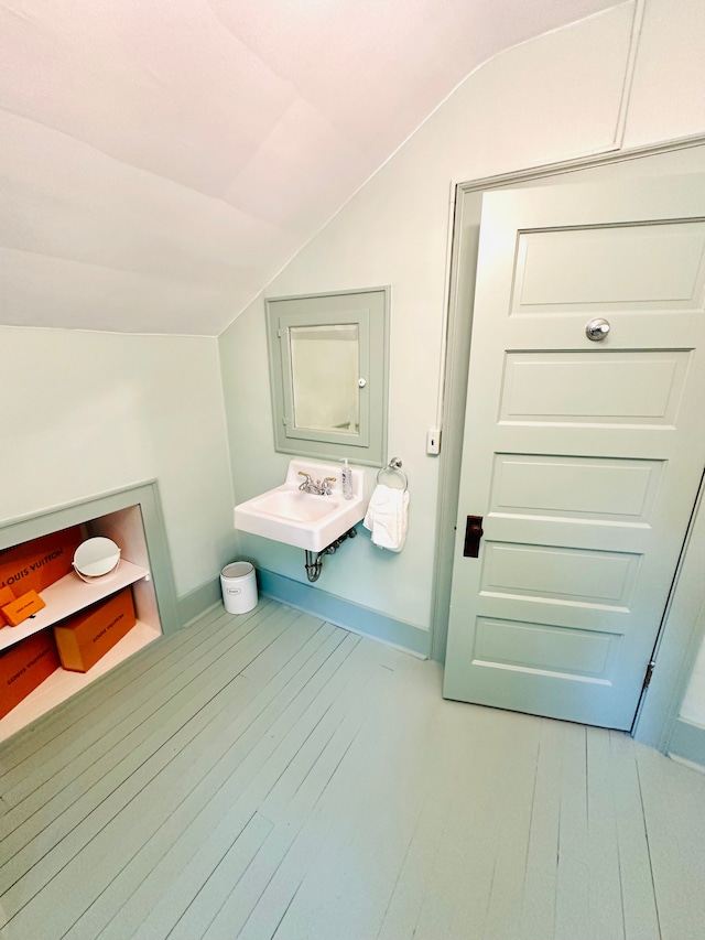 bathroom featuring hardwood / wood-style floors, vaulted ceiling, and sink