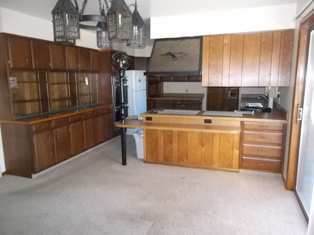 kitchen with hanging light fixtures, multiple ovens, custom range hood, and light colored carpet