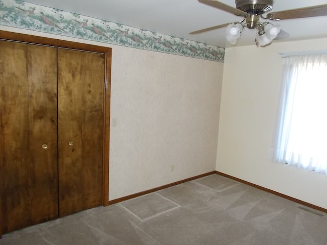 unfurnished bedroom featuring multiple windows, carpet, ceiling fan, and a closet