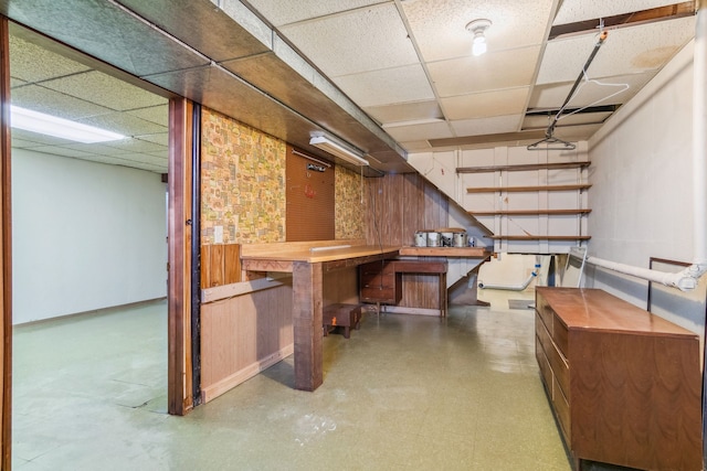 basement featuring a paneled ceiling and a workshop area