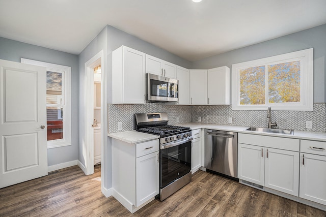 kitchen with backsplash, stainless steel appliances, sink, white cabinets, and dark hardwood / wood-style floors