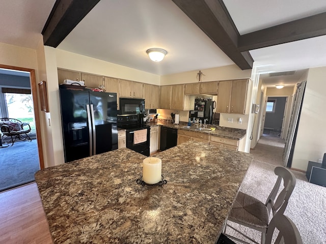 kitchen featuring black appliances, sink, beamed ceiling, light hardwood / wood-style floors, and a breakfast bar area