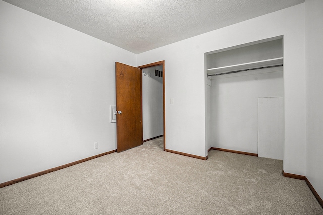 unfurnished bedroom featuring light colored carpet, a textured ceiling, and a closet