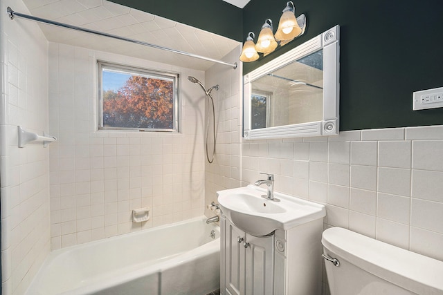 full bathroom with tiled shower / bath, vanity, toilet, and tile walls